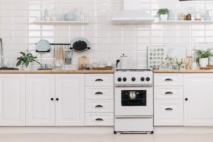 White Wooden Kitchen Cabinets With Dishware and Stove